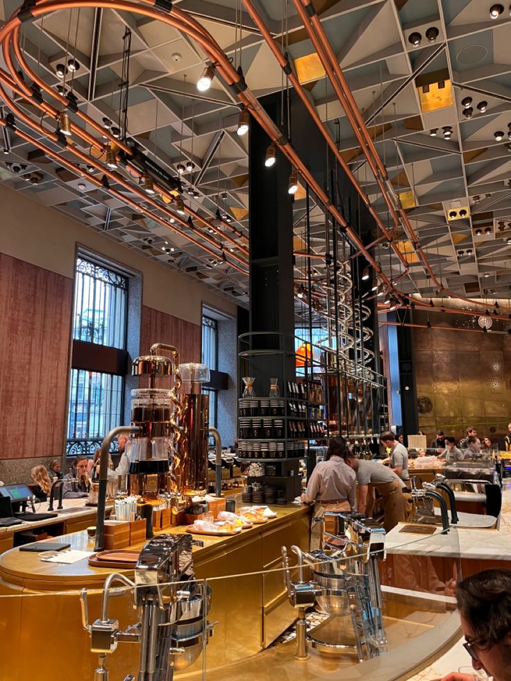 people sitting at tables in a restaurant with lots of copper pipes hanging from the ceiling