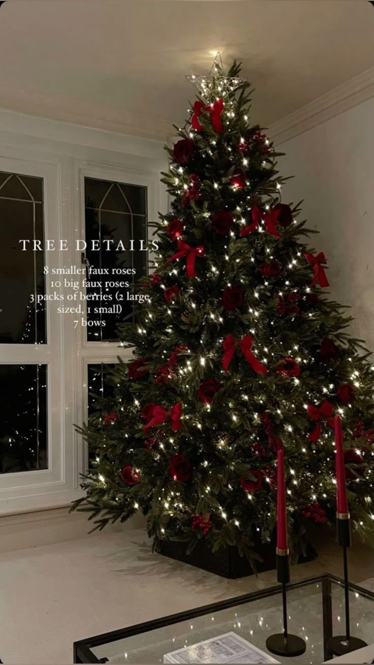 a christmas tree with red bows and lights in front of a large window at night