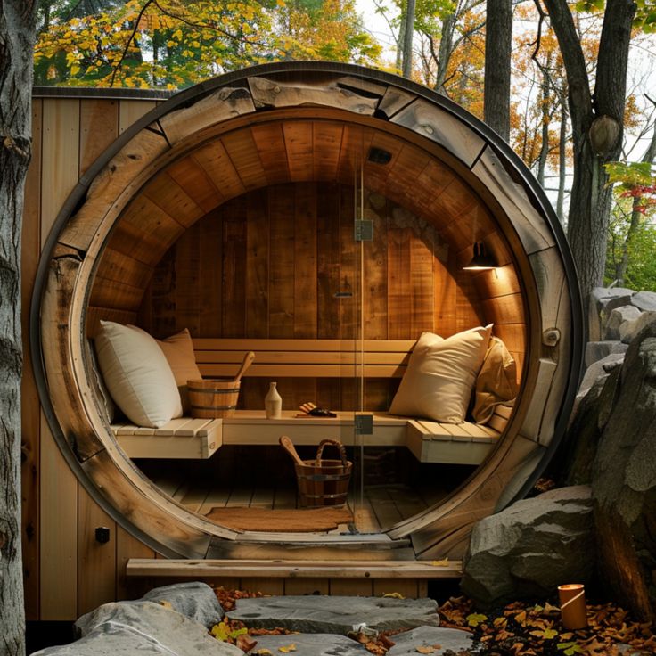 a wooden sauna in the middle of some rocks and trees with pillows on it