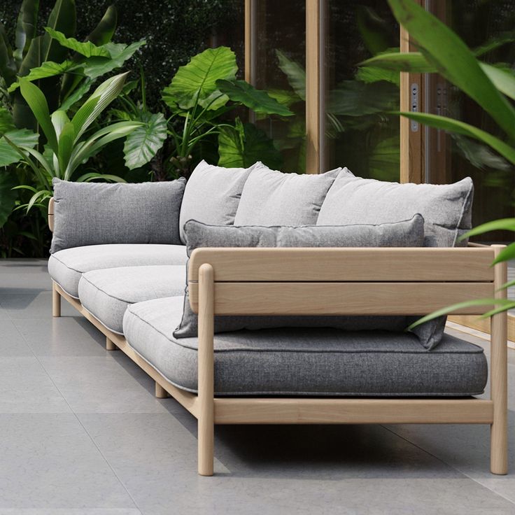 a couch sitting on top of a tiled floor next to plants