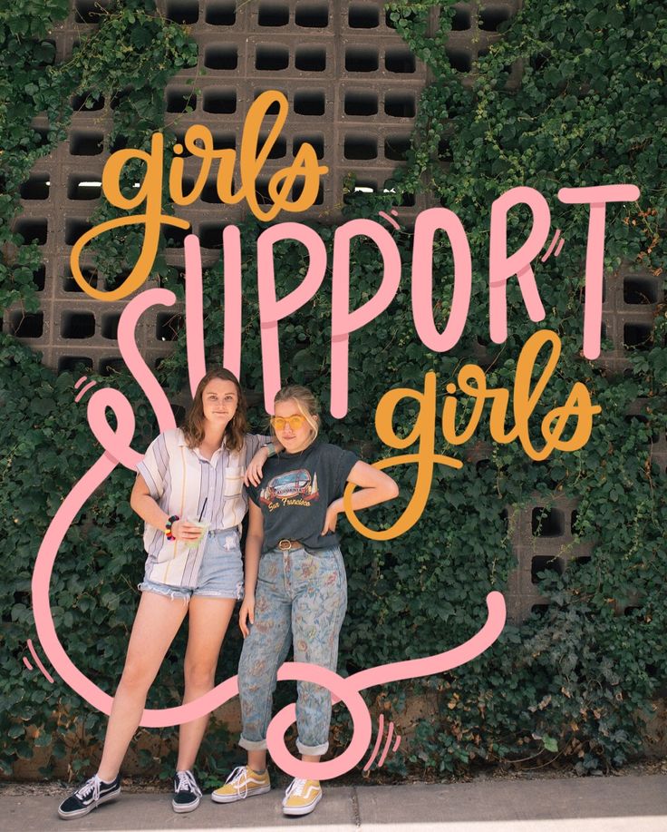 two girls standing next to each other in front of a sign that says girls support girls