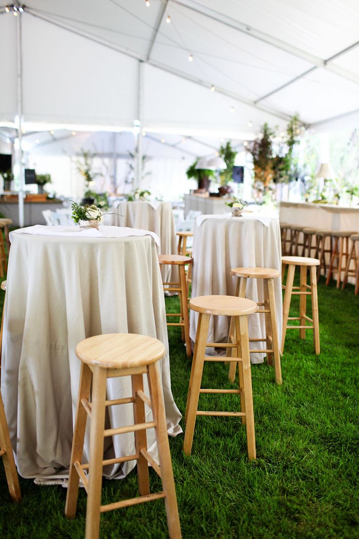 tables and stools are set up under a tent for an outdoor wedding or reception