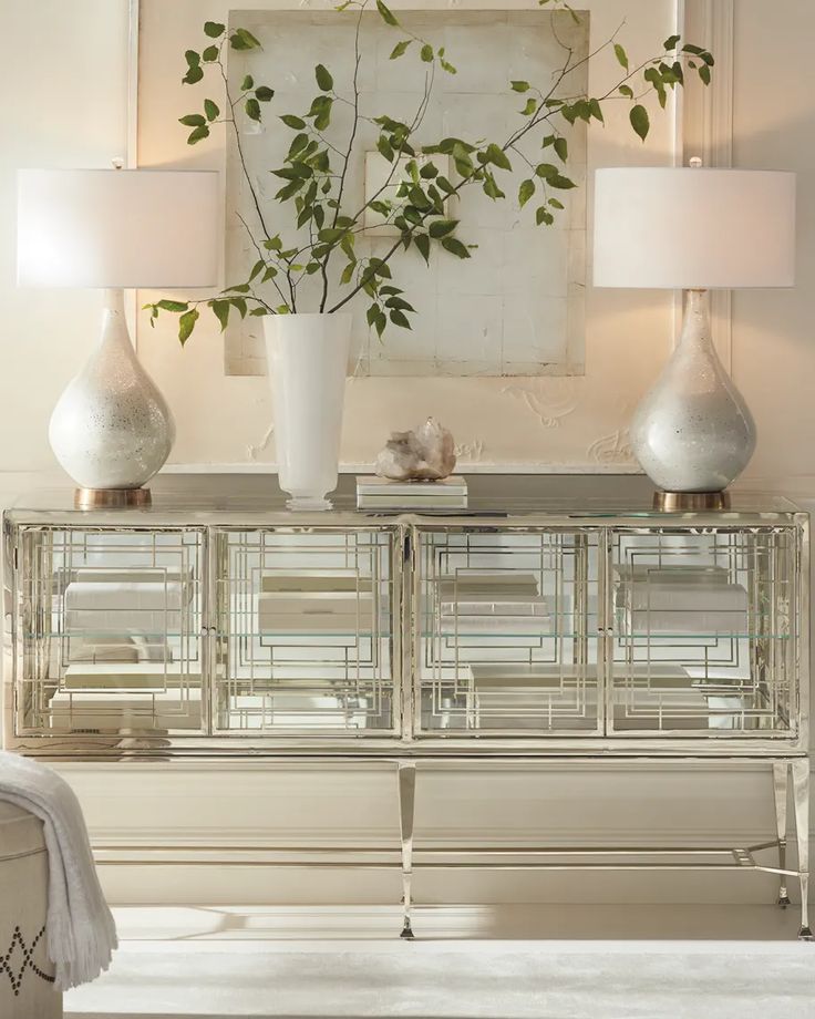 a mirrored cabinet with two lamps and a plant in the middle on top of it