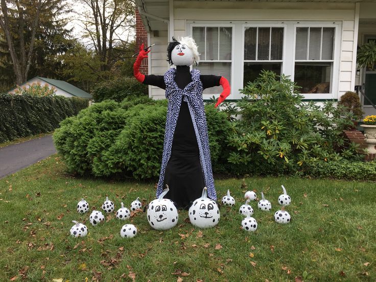 a scarecrow in front of a house with lots of soccer balls on the lawn