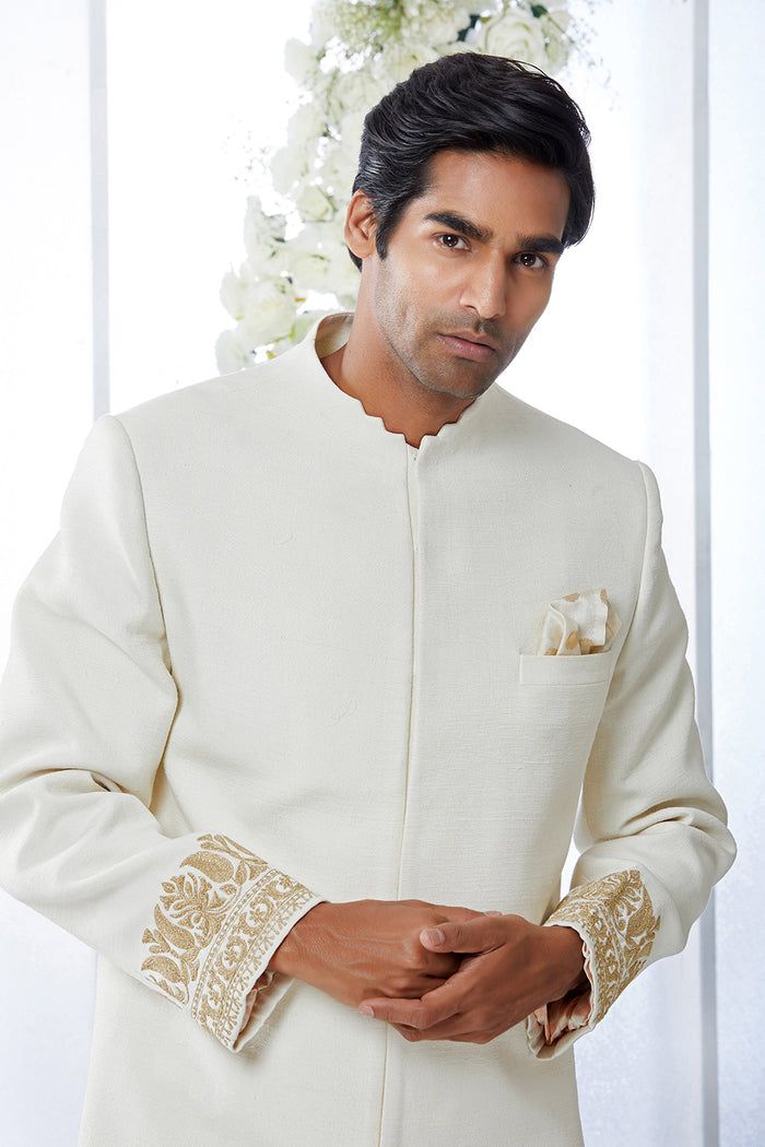 This ivory sherwani set features kiran dori embroidery on the cuffs and a stepper collar detail on a matka silk base. This ensemble is paired with a cotton silk kurta and a stretchable cotton silk trouser. Complimenting footwear is also available.From Seema Gujral's Tuscan Summer collection. DELIVERY TIMEPlease allow 8-12 weeks for your outfit to arrive.FABRIC DETAILSMatka SilkProfessional cleaning only. Elegant Raw Silk Nehru Jacket With Naqshi, Elegant Cream Bandhgala With Chikankari Embroidery, Cream Long Sleeve Bandhgala With Resham Embroidery, Formal Cream Nehru Jacket With Chikankari Embroidery, Cream Sherwani With Chikankari Embroidery And Long Sleeves, Cream Long Sleeve Sherwani With Chikankari Embroidery, Cream Nehru Jacket With Zari Work Long Sleeve, Cream Long Sleeve Bandhgala For Eid, Embroidered Cream Nehru Jacket For Wedding