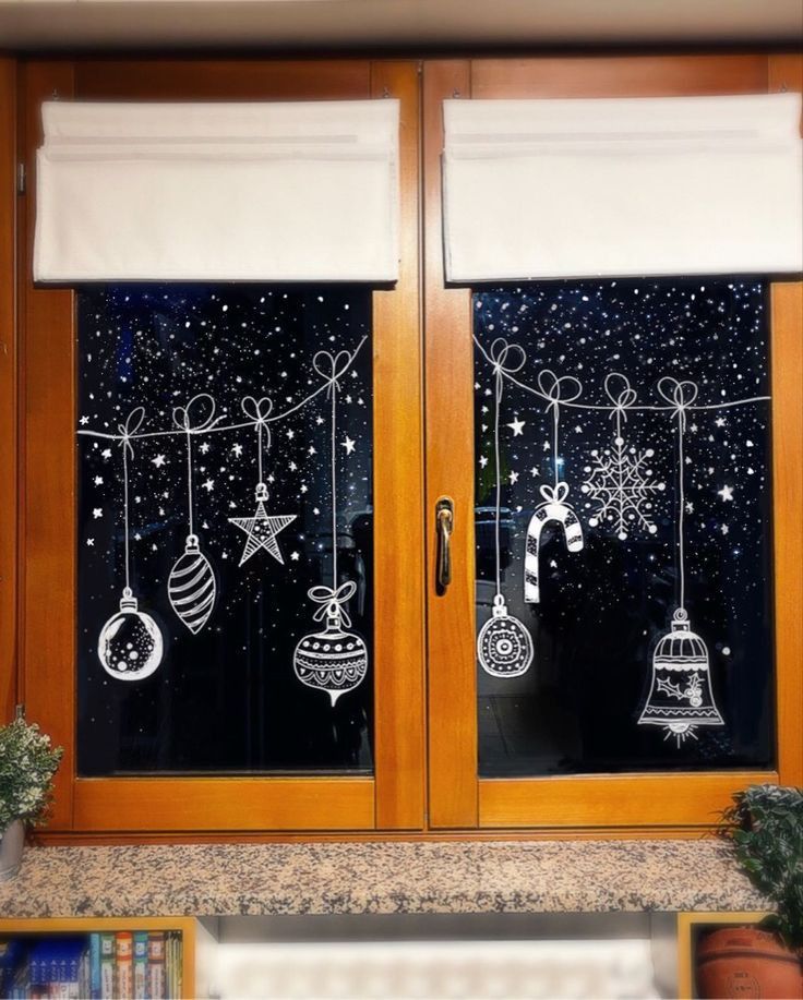 two windows with christmas decorations drawn on them