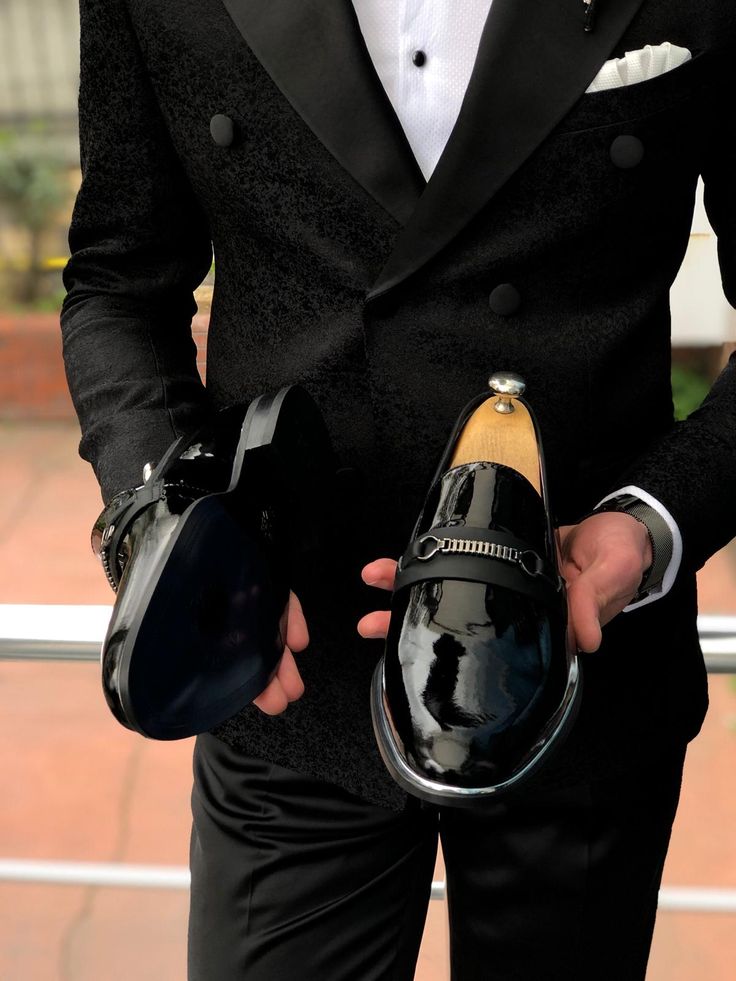 a man in a tuxedo holding two hats