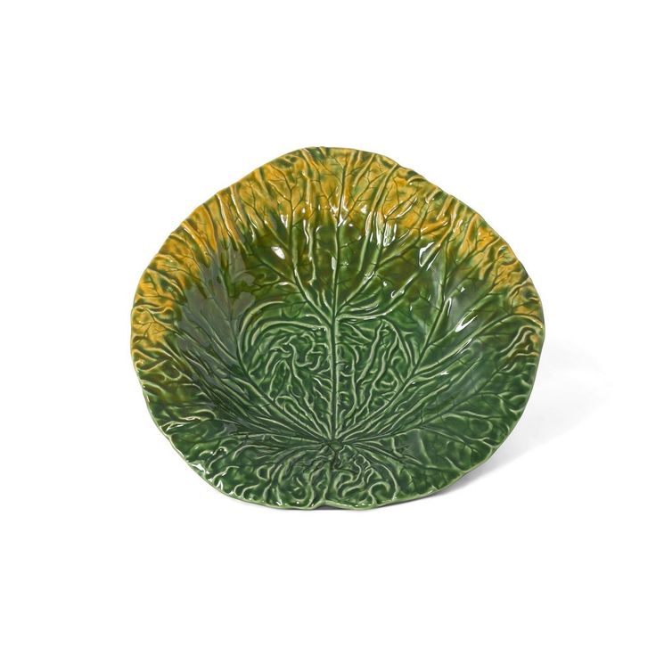 a green and yellow plate with an intricate design on the rim, against a white background