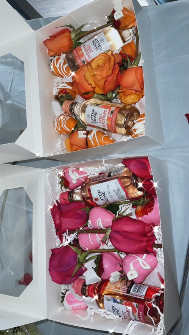 two white boxes filled with roses and bottles of alcohol sitting on top of a table