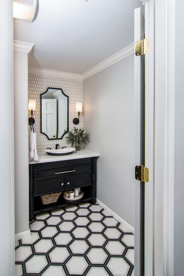 a bathroom with a black and white tile floor, mirror, sink and light fixture