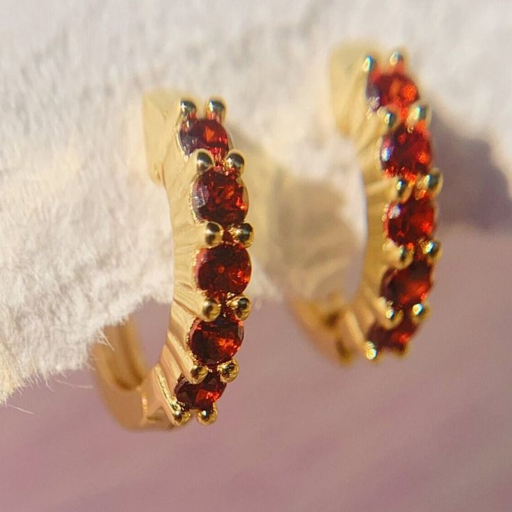 Add serious shine to your ear stack. These Garnet huggies are adorned with glistening gemstones adding a sense of royalty to your ensemble. These dainty garnet earrings hug tightly around the earlobe. Perfect for stacking with more huggies, studs or ear cuffs. Garnet is also known as January birthstones. D E T A I L S - Materials: 14k gold over sterling silver. They are 14k gold THICK plated, and they can last for a very long time with proper care. - Stone: 5 high-grade  garnet cz stones. - Inner diameter: 9mm. Outer diameter: 12mm. - Hypoallergenic, nickel, and lead-free. H O W ∙ T O ∙ O R D E R Select your gemstone in the drop-down menu.  O T H E R ∙ I N F O R M A T I O N * All items are nicely packaged and ready to gift in elegant jewelry boxes. * If you can't find the information you n Gift Round Hoop Earrings With Sparkling Stones, Dainty Birthstone Huggie Earrings For Anniversary, Small Hoop Huggie Earrings With Sparkling Stones For Gift, Red Huggie Earrings For Gift, Red Huggie Earrings Gift, Anniversary Small Hoop Earrings With Birthstone, Sparkling Stone Huggie Earrings For Anniversary, Dainty Gemstone Huggie Earrings In Small Hoop, Anniversary Huggie Earrings With Sparkling Stones