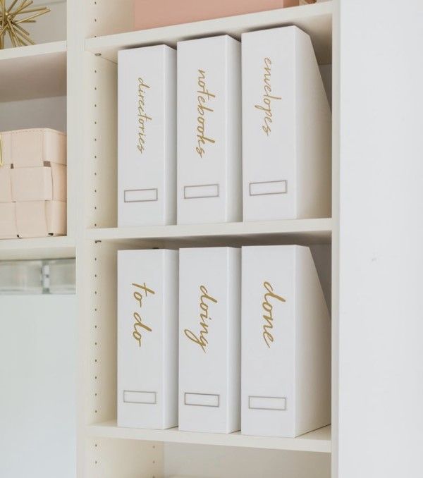 three white boxes with gold lettering on them are sitting on the shelves in front of a mirror