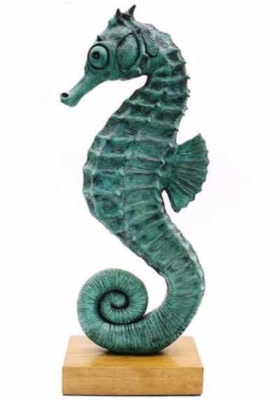 a green sea horse statue sitting on top of a wooden base with a white background