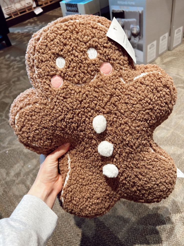 a person holding up a large brown teddy bear with white dots on it's face