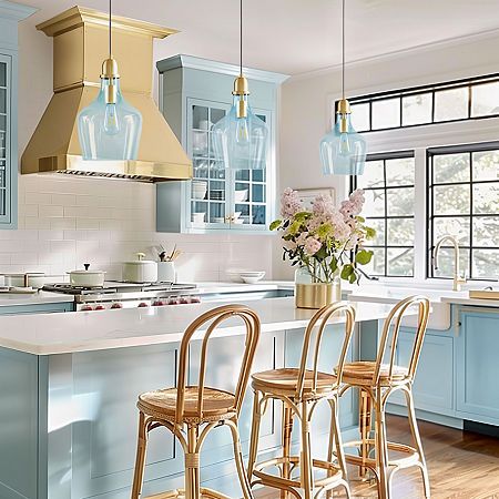 a kitchen with blue cabinets and white countertops has gold accents on the island, along with three stools