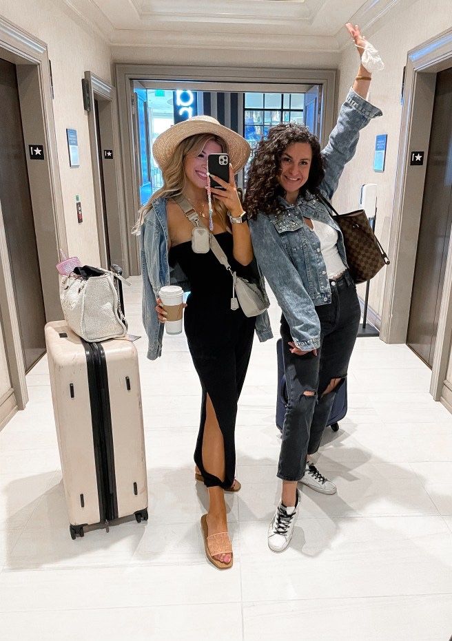 two women taking a selfie in an airport hallway with suitcases and luggage behind them