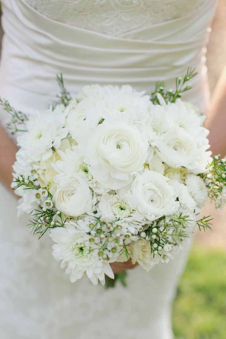 a bride holding a bouquet of white flowers