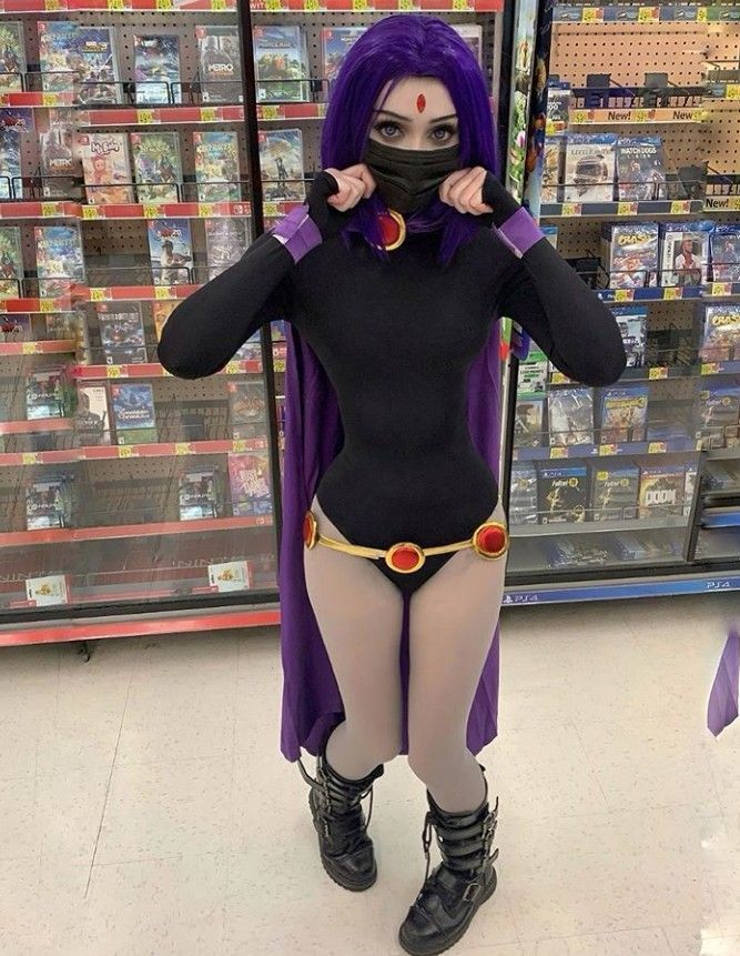 a woman in a black bodysuit and purple hair is standing in front of a store display