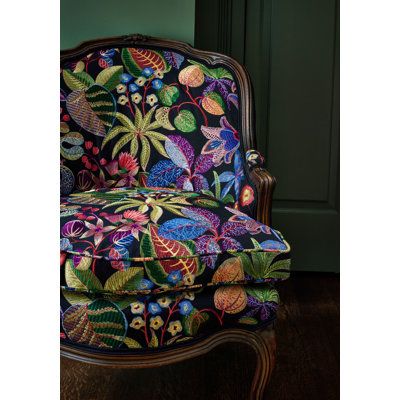 a colorful chair sitting on top of a wooden floor next to a green painted wall