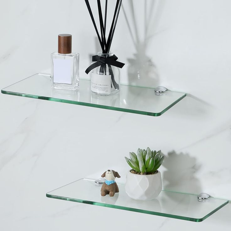 two glass shelves with plants and bottles on them, one shelf has a candle holder