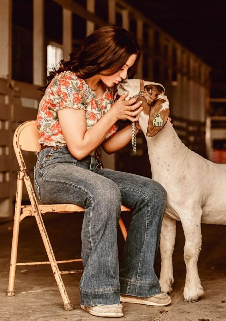 a woman sitting on a chair next to a goat