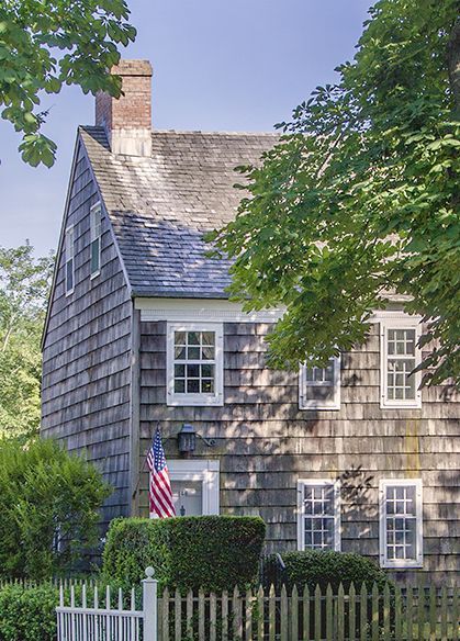 a house with a white picket fence and an american flag on the front door is shown