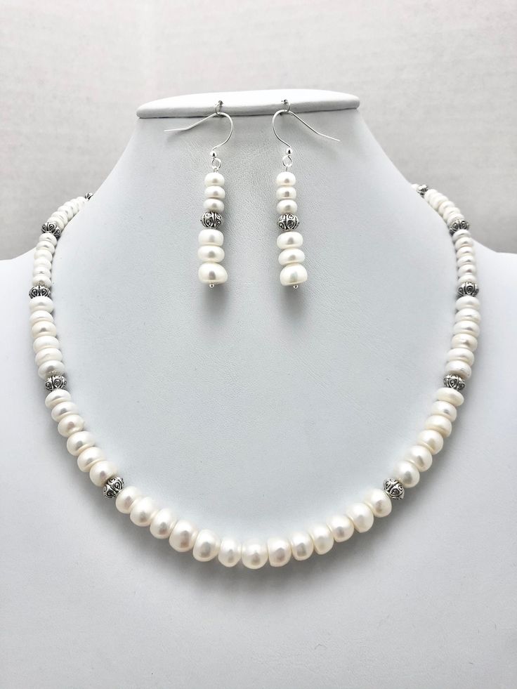 "DESCRIPTION:  This necklace features  a strand of lustrous, white button-shaped pearls in a \"graduated\" style pattern. Larger pearls are in the front portion of the necklace, and smaller pearls are in the back portion of the necklace. The strand of pearls is accented with textured silver saucer-shaped beads that add interest and variety to the simple design. I finished the necklace with a silver-plated toggle clasp that matches the shape of the pearls (see the seventh photo). It is easy to fasten and and secure when the necklace is worn.  This necklace is so classy and elegant. It is also lightweight and comfortable to wear. No jewelry collection is complete without a simple strand of pearls. The  silver beads that were included in the design adds an updated, modern look to a classic de Classic White Pearl Necklace With Pearl Drop, Classic White Single Strand Pearl Necklace, Classic White Pearl Drop Necklace, Classic White Beaded Pearl Necklace, Classic White Beaded Necklaces, Classic White Beaded Necklace, Classic White Pearl Necklace With Pendant, Formal White Single Strand Pearl Necklace, White Round Pearl Drop Necklace