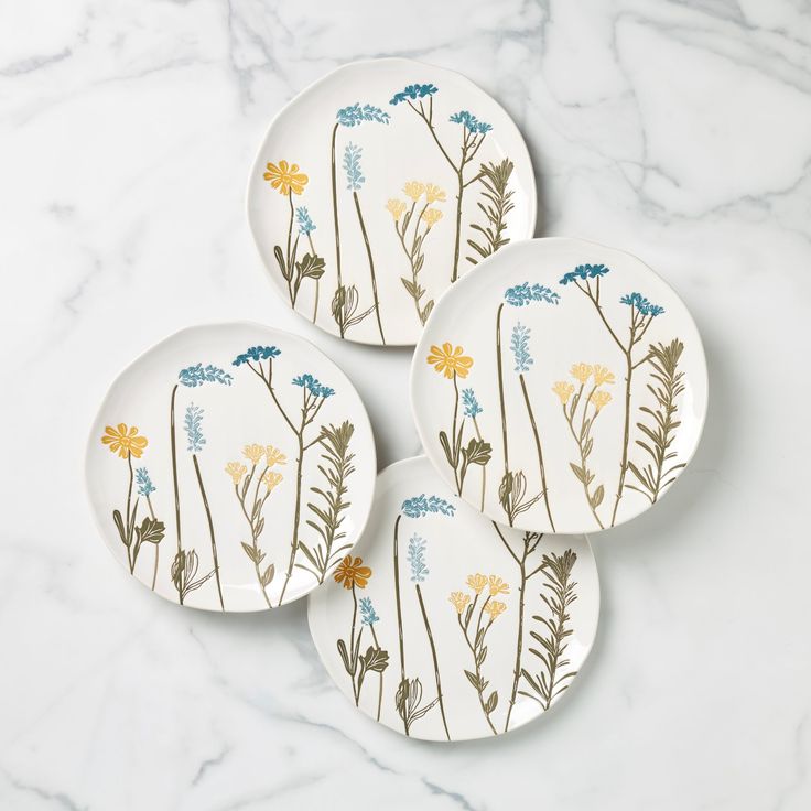 three plates with flowers painted on them sitting on a marble table top next to each other