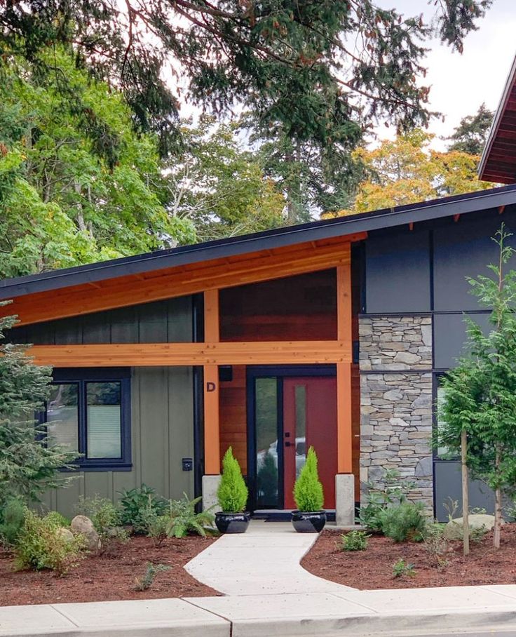 a modern home with stone and wood accents in the front yard, along with landscaping