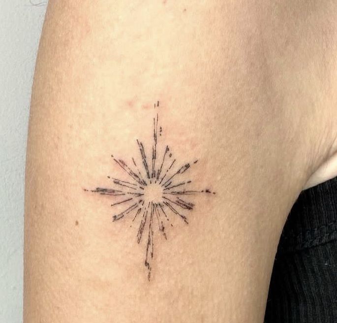 a small starburst tattoo on the back of a woman's left arm