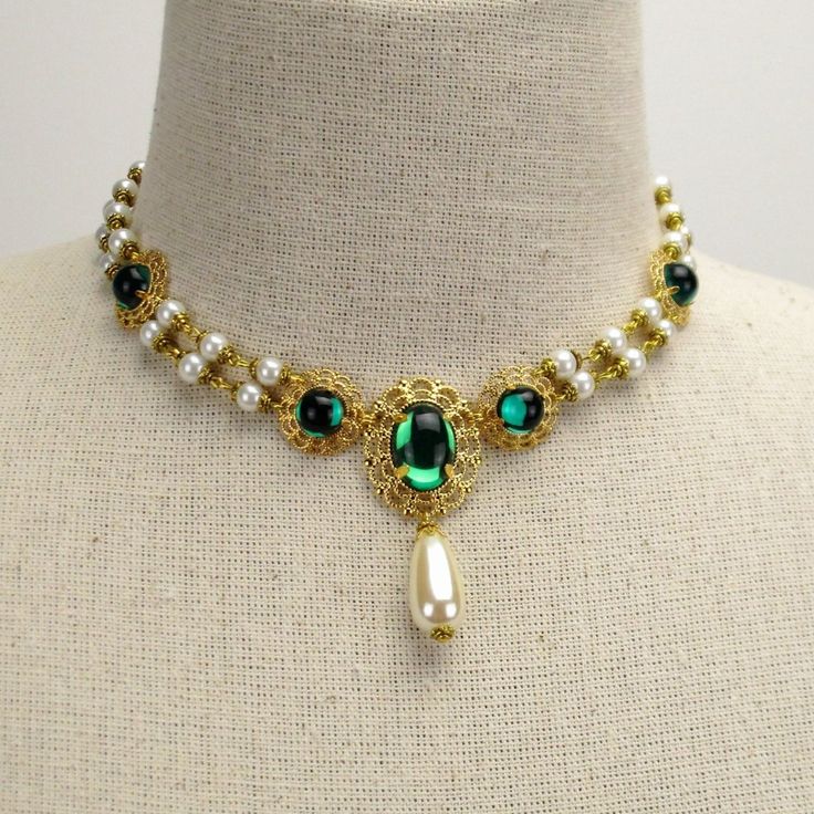 Milady Pauline Necklace in Antique Gold, Pearls & Emerald Green Gems A drop of color can go a long way when you want to stand out of the crowd. With its sophisticated style and colorful gems, the vibrant yet elegant Milady Pauline necklace adds the best of both worlds to your Victorian or Renaissance wedding attire. This stunning Renaissance-inspired pearl necklace features double strands of incandescent chained pearls capped in antique gold between stations of emerald green gems mounted in Gold And Green Necklace, Gold And Emerald Necklace, Necklace Reference, Emerald Necklace Gold, Double Strand Pearl Necklace, Alicent Hightower, Victorian Necklace, Historical Jewellery, Medieval Jewelry