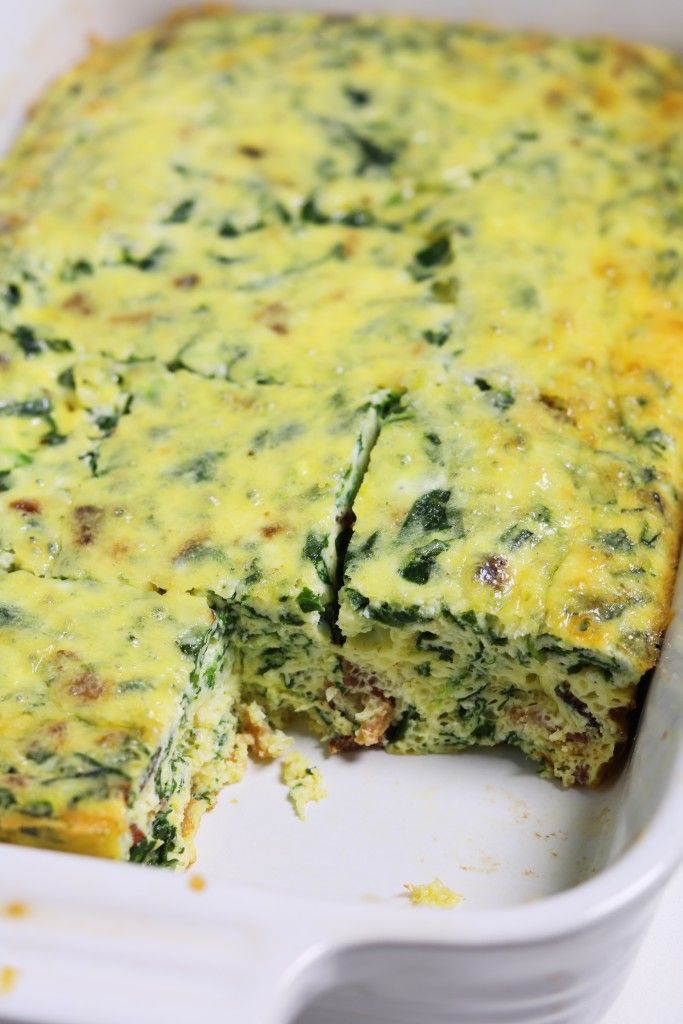 a casserole with spinach and cheese in a white dish on a table