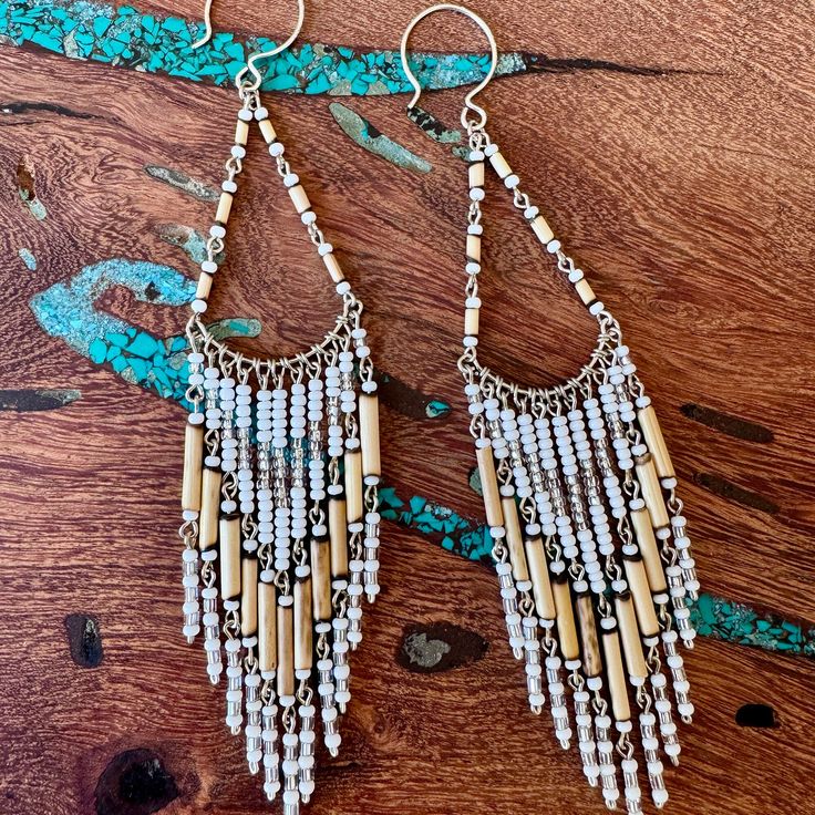 💌 DESCRIPTION Long Fringe Earrings, White with Bamboo. Cowgirl up, ladies! These wonderful chandelier style earrings will help make a statement when it's time to say Howdy and Yee-Haw! Made using czech seed beads, wire and wonderful bamboo tube beads, they are hung onto a sterling silver earwire that doesn't need a back to stay on. They're long - 4.5" total.  I like to call the look of these earrings "Boho Tribal" ️ 💌 SIZE 4.75" Length 1" Wide 💌 COLORS White, tan, silver 💌 MATERIALS Czech glass seed beads Bamboo tube beads Sterling Silver ear wires 💌 PROCESSING . TIME Most pieces are already made and ready to ship. On occasion, I will need to make you one from scratch. When that happens, it only will add 1-2 days onto the production time. Otherwise you can expect your package to ship Beaded Dangle Earrings In Brass, Bohemian Teardrop Beaded Earrings For Pierced Ears, Festival Brass Beaded Earrings With Ear Wire, Bohemian Crystal Drop Earrings With Ear Wire, Bohemian Pearl Drop Earrings, White Bohemian Dangle Pearl Earrings, White Bohemian Jewelry With Dangling Beads, Bohemian White Dangle Pearl Earrings, Bohemian Gold Beaded Crystal Earrings