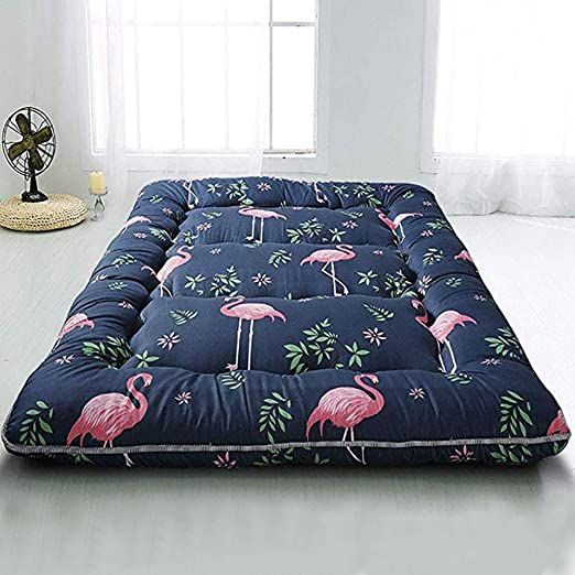 a blue and pink flamingo print futon mattress on a white floor next to a window