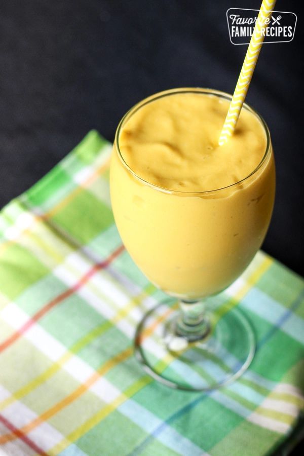 a smoothie in a glass with a straw on the top and text overlay that reads mango avocado smoothie