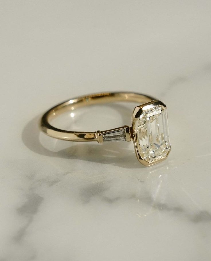 an engagement ring with a large diamond in the center on a marble countertop top