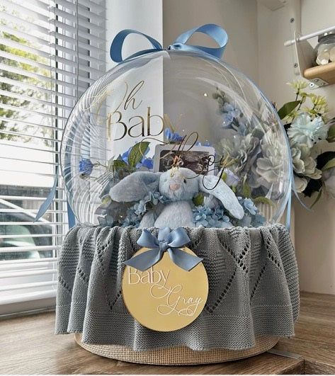 a clear ball with blue flowers and a teddy bear in it sitting on a table