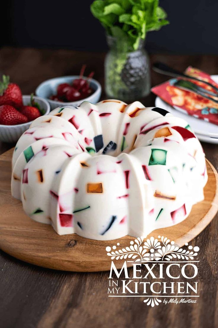 a bundt cake sitting on top of a wooden table next to bowls of strawberries