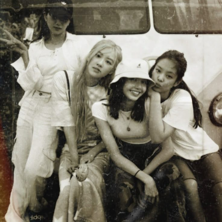 four young women are posing in front of a bus