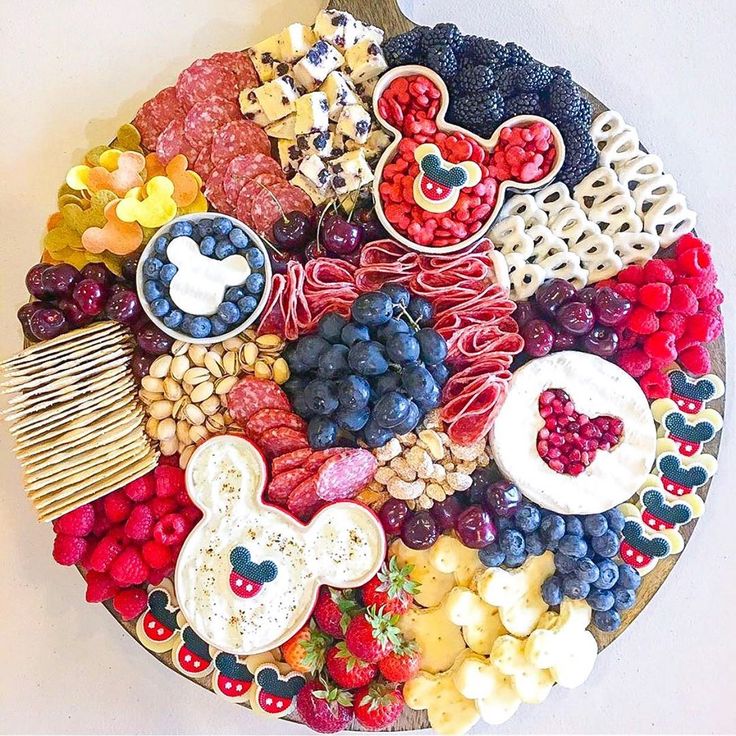 a platter with mickey mouse cookies, berries, strawberries, and other snacks