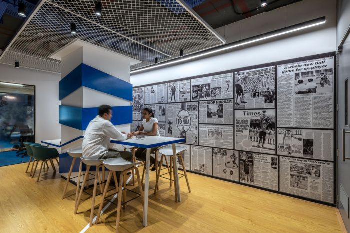 two people sitting at a table in front of a wall with newspaper pages on it