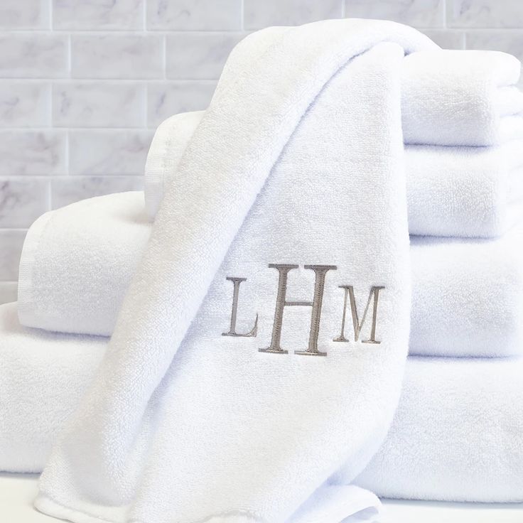 towels stacked on top of each other with the word lhm written in silver