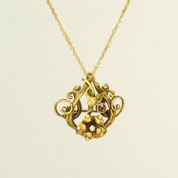 This lovely antique Art Nouveau diamond and garnet flower necklace is wonderful. It is versatile because it is also a pin and can be worn many ways. It is on a chain currently which makes it a beautiful necklace but can be easily slipped off and worn as a brooch. This pin is from the 1890s. Antique Pin/PendantArt Nouveau 1890sDiamondGarnet 14k Yellow GoldPin Size:1 " by 1 1/8"Chain Size: 18" long Antique Formal Necklace With Brooch, Antique Formal Necklaces With Brooch, Antique Necklace With Brooch For Formal Occasions, Heirloom Style Formal Necklace With Brooch, Fine Jewelry Necklaces With Brooch For Anniversary, Anniversary Pendant Necklaces With Brooch Detail, Anniversary Pendant Necklace With Brooch Detail, Victorian Pendant Necklace With Brooch Detail, Diamond Necklace With Brooch For Wedding