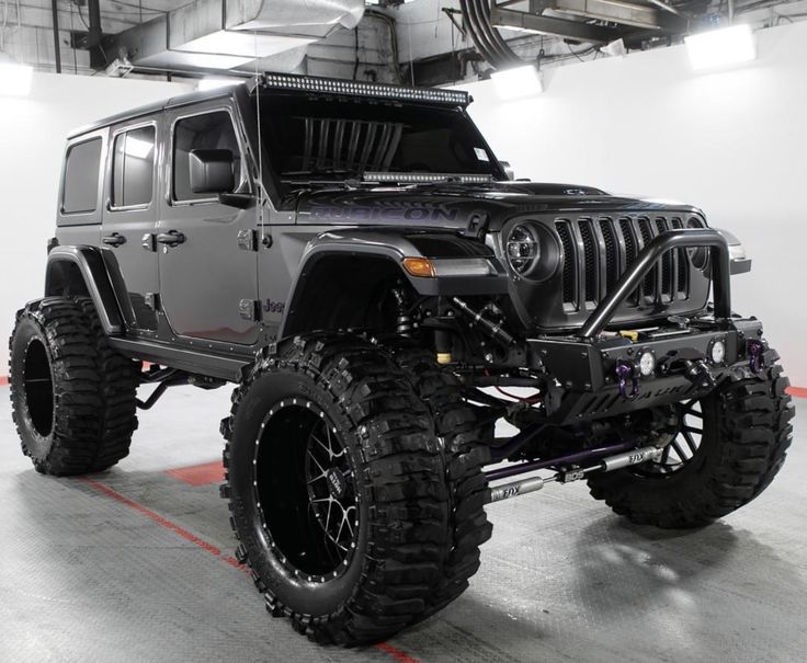 a black jeep parked in a garage with its lights on and the front bumper lifted up