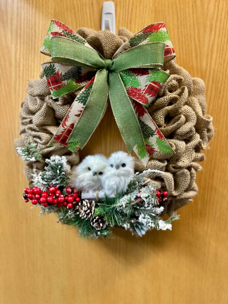 a christmas wreath with two small white dogs on it hanging from a door hanger