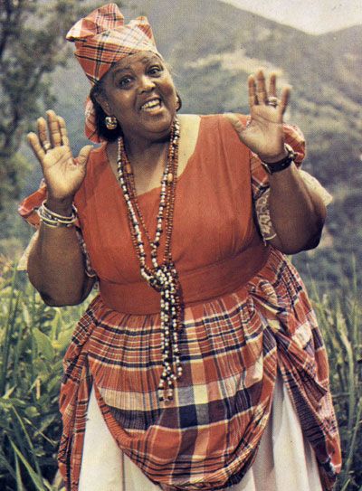 a woman in an orange dress is holding her hands up and making the peace sign