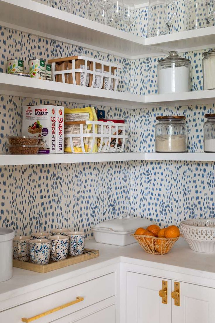 a kitchen with blue and white wallpaper, shelves filled with dishes and containers on top of them