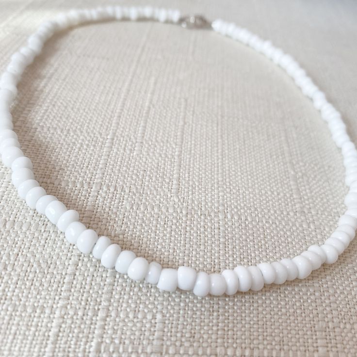 This white seed-beaded choker is super cute to add a pop of color to any outfit or to go with any occasion! Its made with beading wire (non-stretchy). The standard choker length is 15 inches long. If you message me on Instagram or Etsy I can make the choker smaller or bigger to fit you. For best care stay away from water! Size: 15 inches long Things included in your package (bubble mailer) : -your order -thank you card -extras (stickers or candy) Make sure you follow my Instagram @jewelrybynausheen for amazing jewelry posts and shop updates! White Beaded Choker For Summer, White Tiny Beads Choker For Summer, White Summer Choker With Tiny Beads, Summer White Choker With Tiny Beads, White Round Beads Choker For Beach, Dainty White Beaded Necklaces For Summer, Dainty White Beaded Necklace For Summer, White Beaded Necklaces With Tiny Beads For Everyday, White Tiny Beads Choker For Beach