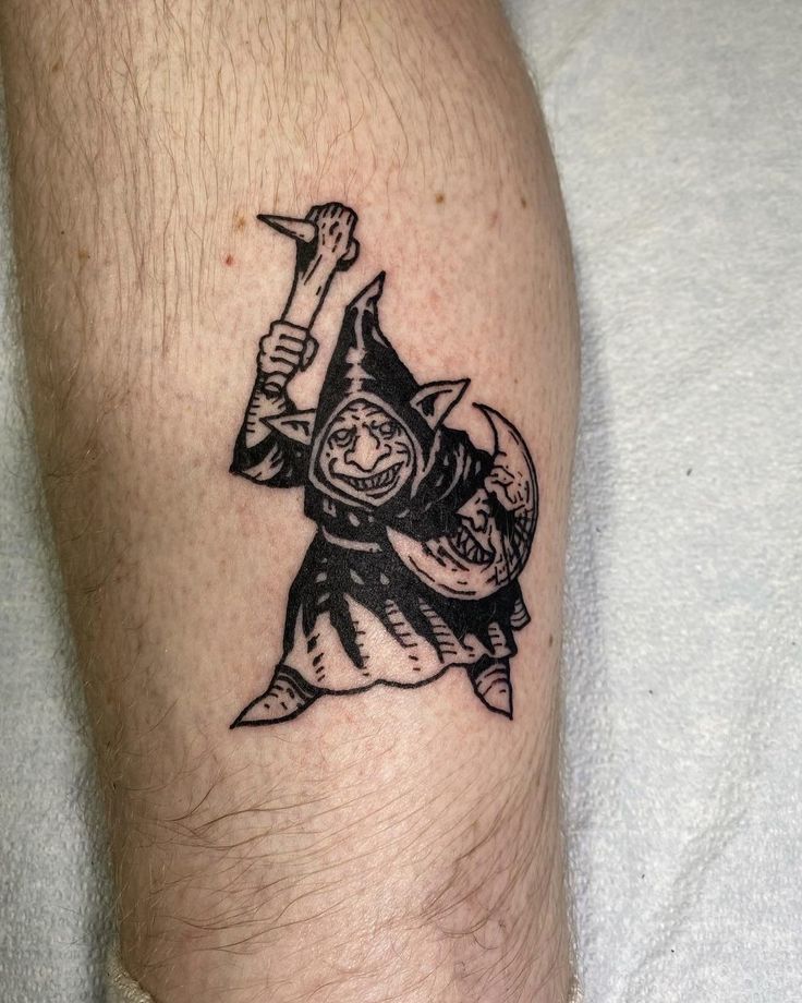 a tattoo on the leg of a man with a wizard hat and holding a hammer