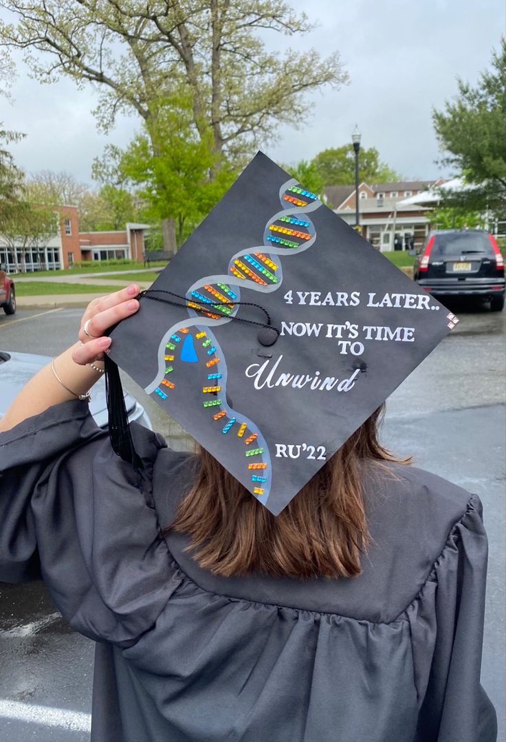 Graduation cap with a DNA helix unwinding by a DNA helicase. To the right of the DNA strand says “4 years later.. Now it’s time to unwind” Bachelors In Biology Cap, Science Graduation Cap Designs, Graduation Cap Designs College Biology, Cap Decoration Graduation Biology, Grad Cap Ideas Biology, Graduation Cap Designs Exercise Science, Biology Graduation Party Ideas, Chemistry Graduation Cap Ideas, Biology Degree Graduation Caps